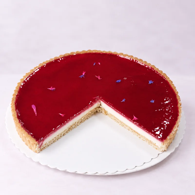 Angeschnittene Himbeer-Panna-Cotta-Tarte mit rotem Fruchtspiegel