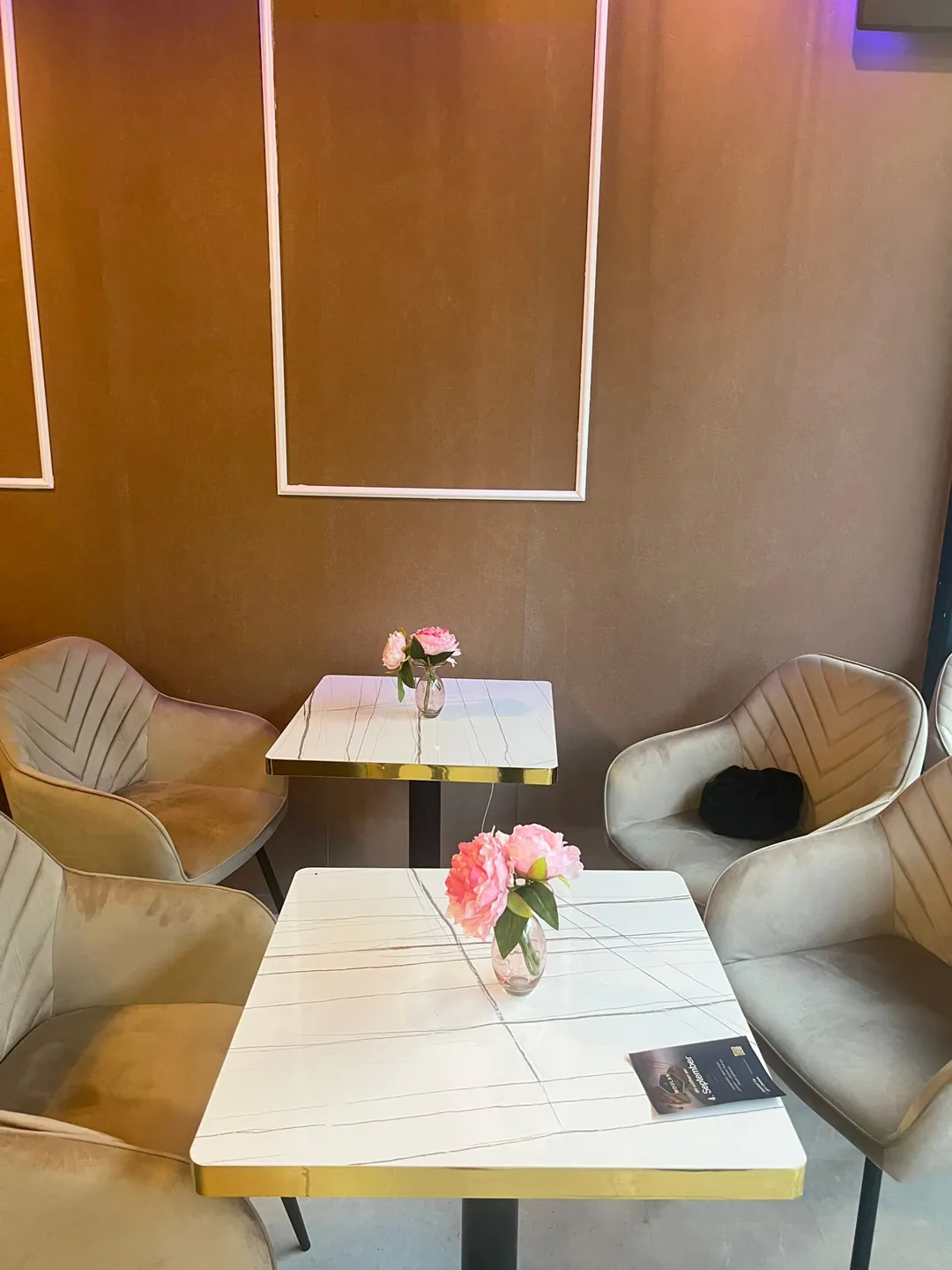 Sitzecke mit Samtsesseln, Marmortischen und frischen Blumen im Moulan Café